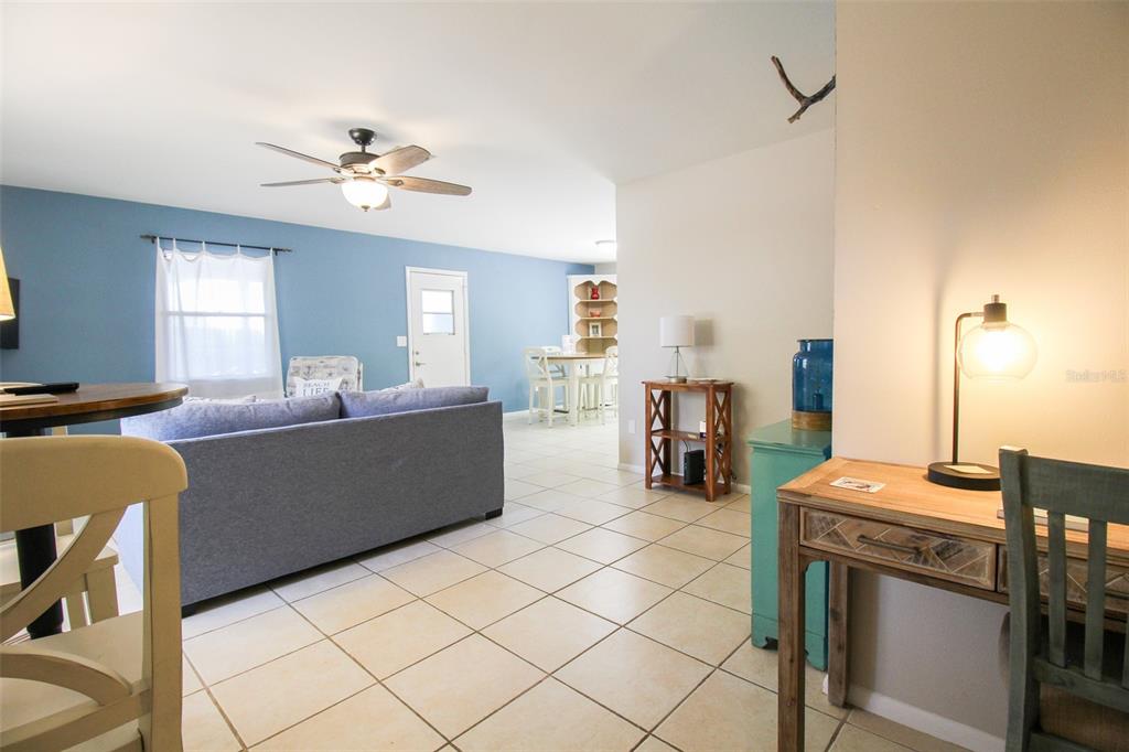 A living room with blue walls, tile flooring, a gray sofa, and a wooden desk — 1116 ROYAL ROAD, VENICE, FL