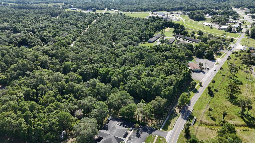 An aerial view shows a large wooded lot adjacent to a road and commercial buildings — 0 S SUNCOAST BOULEVARD, INGLIS, FL