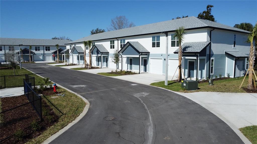A row of modern two-story townhomes with garages and light-colored siding under a clear sky — 1019 E CAROLINE STREET, TAVARES, FL