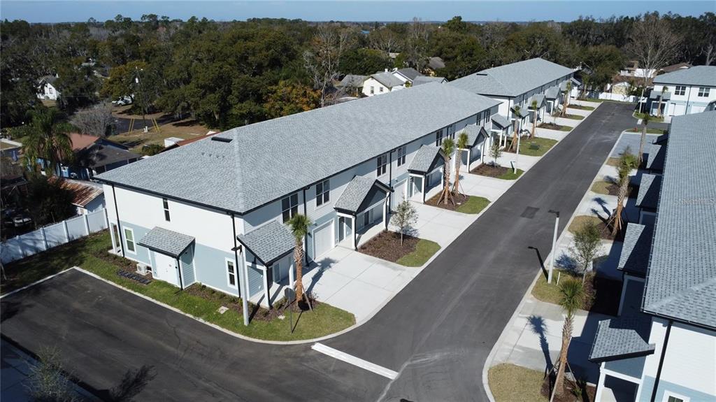 An aerial view shows a row of modern townhouses with gray roofs and paved driveways — 1019 E CAROLINE STREET, TAVARES, FL