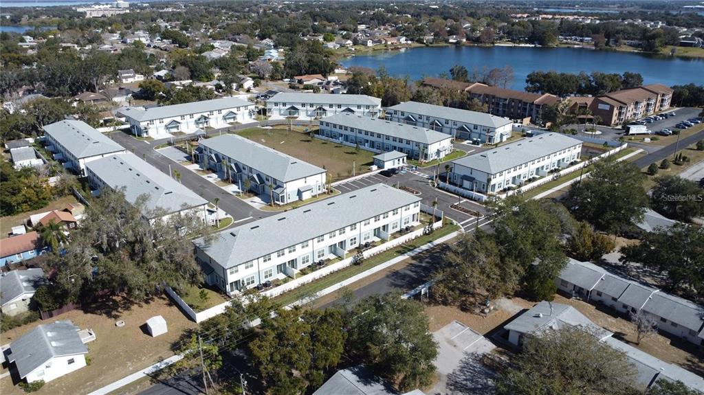 An aerial view shows a residential complex of multi-story townhomes with grey roofs — 1019 E CAROLINE STREET, TAVARES, FL