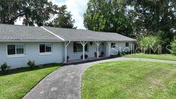 A single-story white house with a gray roof sits behind a long gravel driveway — 2190 SE 39TH STREET, OCALA, FL
