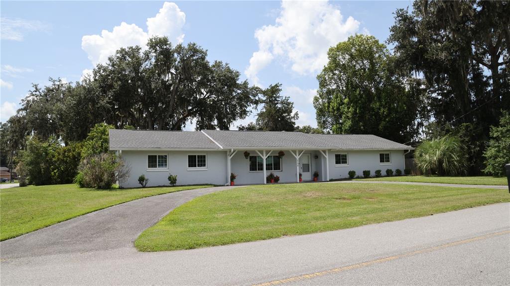 A paved driveway leads toward a house partially obscured by large trees and bushes — 2190 SE 39TH STREET, OCALA, FL