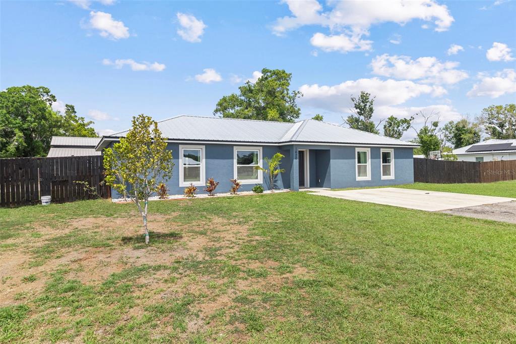 A blue single-story house with a metal roof stands behind a grassy front yard — 1620 SE HAVEN DRIVE, ARCADIA, FL
