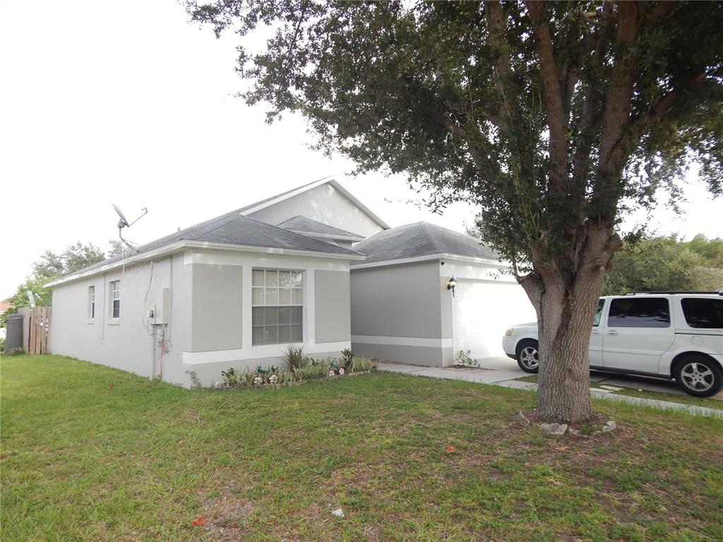 A single-story house with a white garage, gray exterior walls, and a large tree nearby — 3434 CYPRESS POINT CIRCLE, ST CLOUD, FL