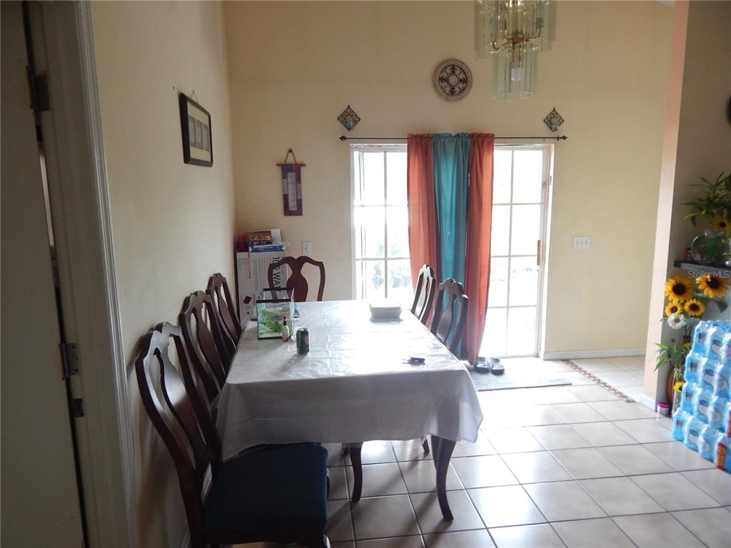 A dining room features a table with chairs, tile flooring, and sliding glass patio doors — 3434 CYPRESS POINT CIRCLE, ST CLOUD, FL