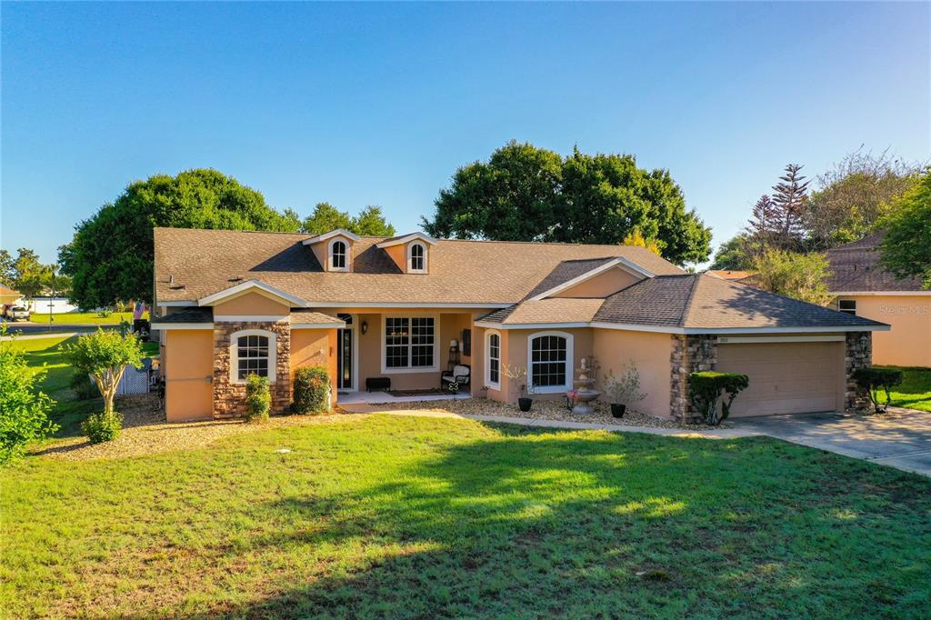 A single-story house with a tan stucco exterior, stone accents, and a two-car garage — 3151 BRIGHTON ROAD, EUSTIS, FL