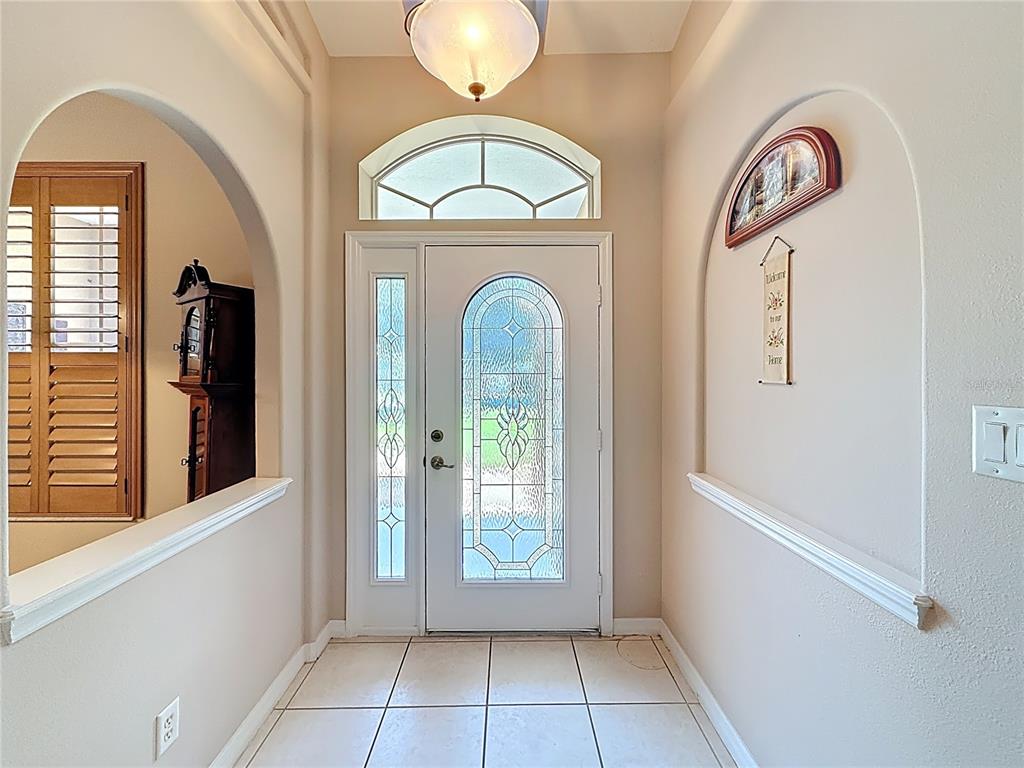 An entryway features a white front door with glass panels, arched wall niches, and tile flooring — 3151 BRIGHTON ROAD, EUSTIS, FL