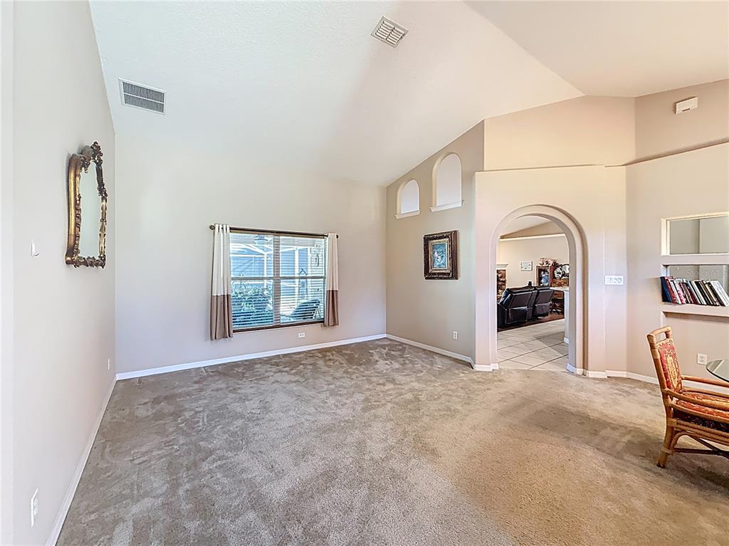 A carpeted living room features vaulted ceilings, an arched entryway, and a built-in wall niche — 3151 BRIGHTON ROAD, EUSTIS, FL