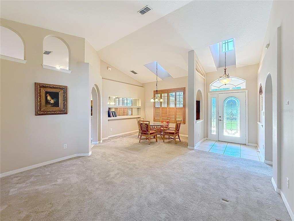 A carpeted living area leads to a dining nook with a skylight and arched niches — 3151 BRIGHTON ROAD, EUSTIS, FL