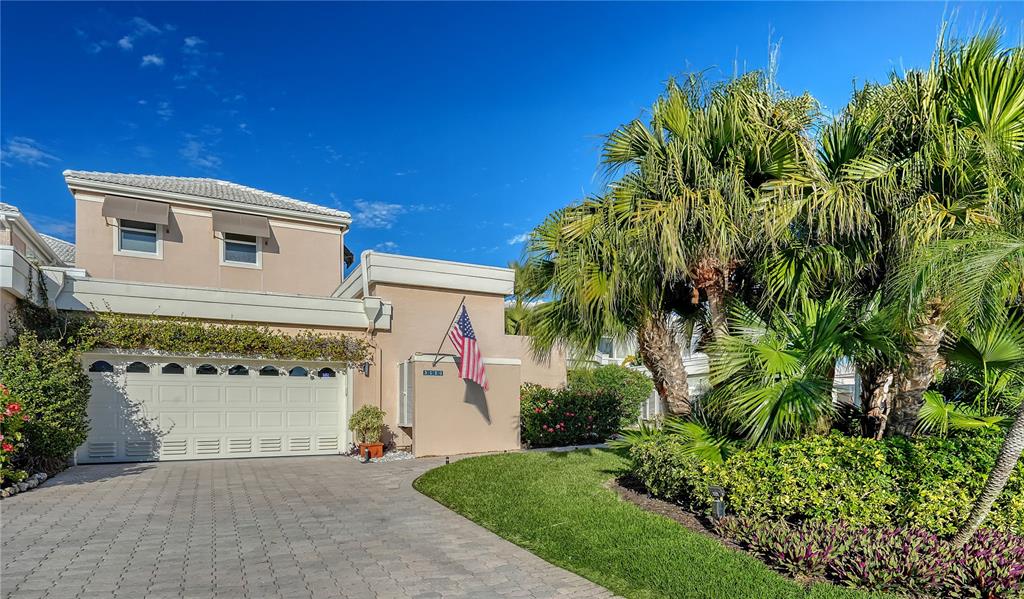 A two-story beige house with a white garage door and a palm tree-lined front yard — 3530 MISTLETOE LANE, LONGBOAT KEY, FL