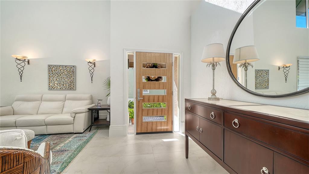 An entryway features a light wood front door, white tile floors, and a dark wood console — 3530 MISTLETOE LANE, LONGBOAT KEY, FL