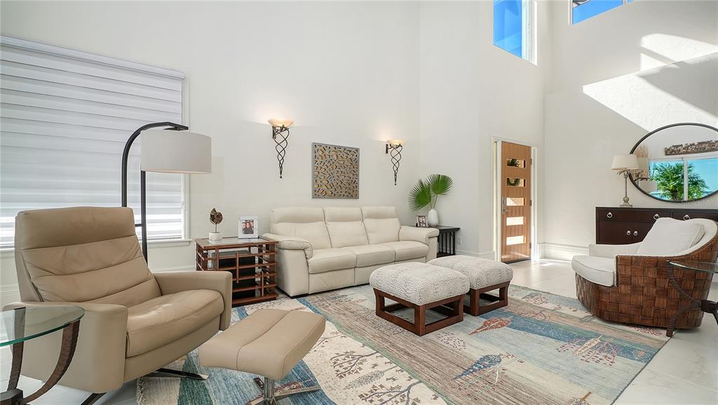 A bright living room features a white sofa, beige leather armchair, and a patterned area rug — 3530 MISTLETOE LANE, LONGBOAT KEY, FL