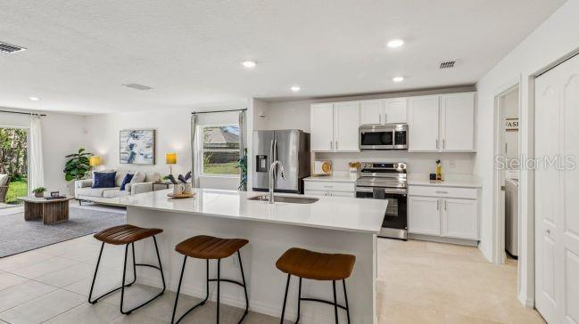 A modern kitchen with white cabinets, a large island, and bar stools overlooks the living area — TBD MIRAGE AVENUE, WEEKI WACHEE, FL