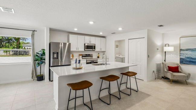 A modern kitchen features white cabinetry, a central island with bar stools, and stainless appliances — TBD MIRAGE AVENUE, WEEKI WACHEE, FL
