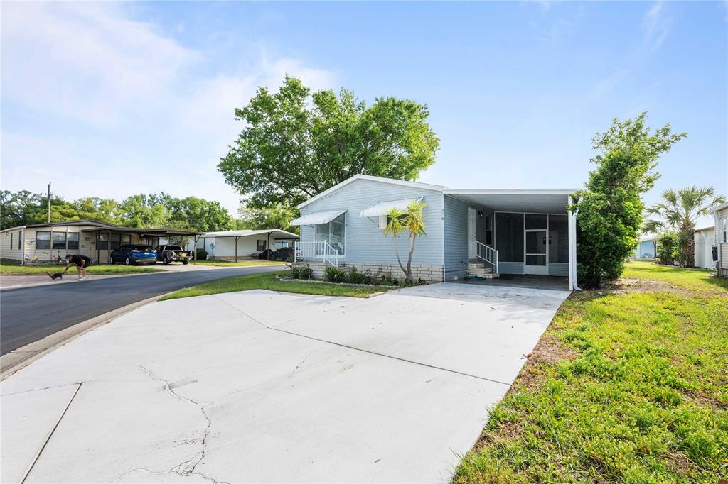 An elevated view of a light blue mobile home with a concrete driveway and carport — 3210 HICKORY DRIVE, WESLEY CHAPEL, FL