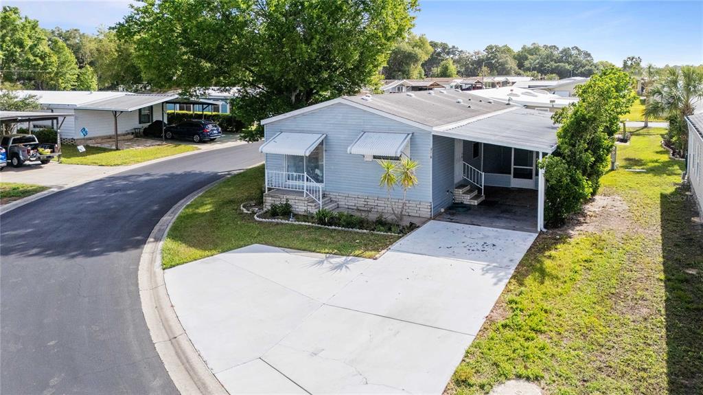 A light blue manufactured home features a front porch, a carport, and a concrete driveway — 3210 HICKORY DRIVE, WESLEY CHAPEL, FL