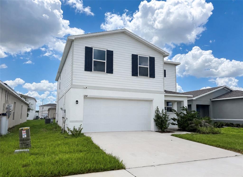 A two-story house with white siding, a two-car garage, and dark window shutters — 1242 CHESTER AVENUE, HAINES CITY, FL