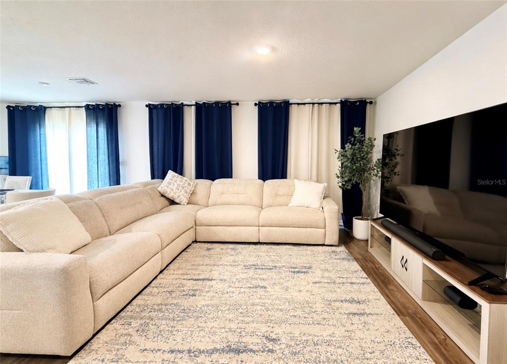 A living room features a large beige sectional sofa, a patterned rug, and a television — 1242 CHESTER AVENUE, HAINES CITY, FL