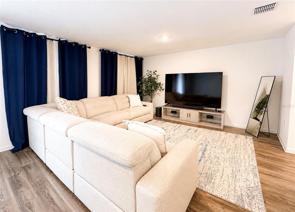 A living room features a large beige sectional sofa, a television on a stand, and curtains — 1242 CHESTER AVENUE, HAINES CITY, FL