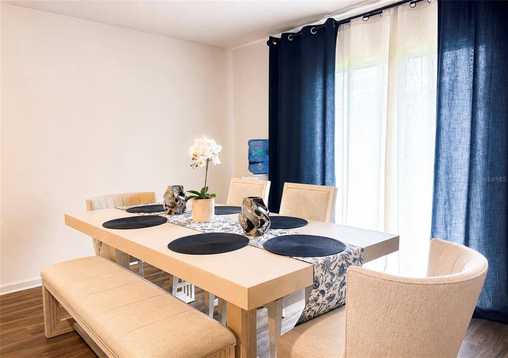 A dining room features a light wood table with a bench, chairs, and blue curtains — 1242 CHESTER AVENUE, HAINES CITY, FL