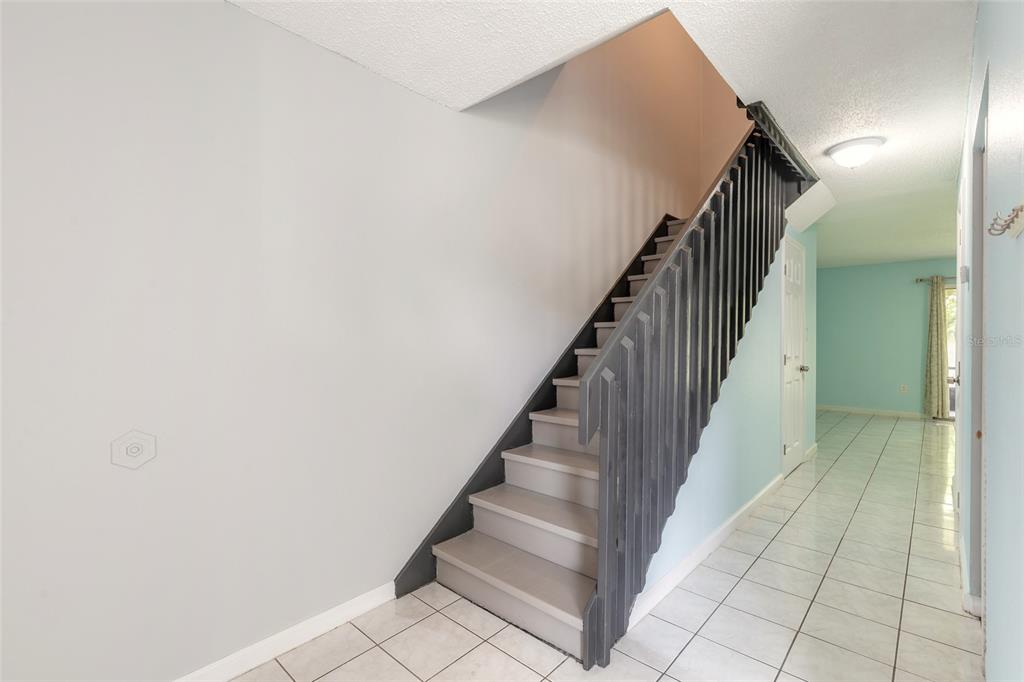 A staircase with a dark railing leads up from a tiled room with blue walls — 5060 DOWNING STREET UNIT 6, ORLANDO, FL