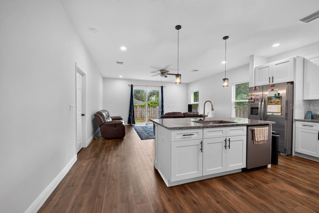 A kitchen with a granite island and stainless steel appliances opens into a living area — 8118 N SEMMES STREET, TAMPA, FL