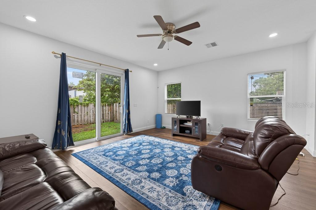 A living room features brown leather sofas, a blue patterned rug, and sliding glass doors — 8118 N SEMMES STREET, TAMPA, FL
