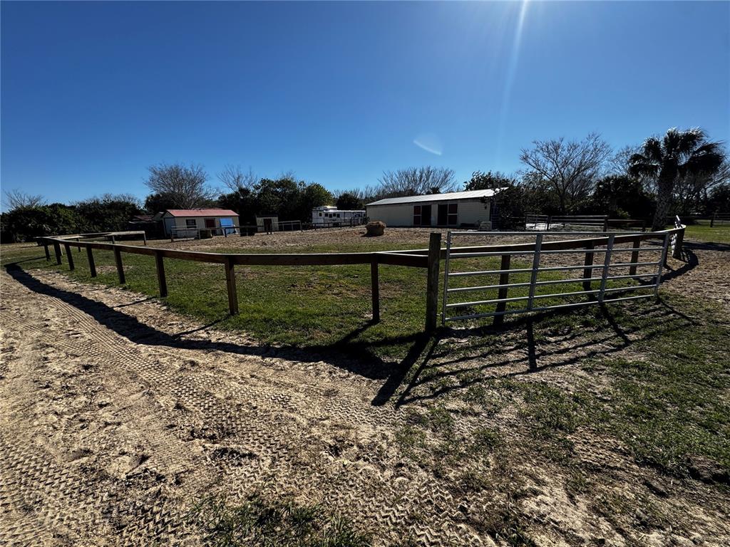 A fenced dirt paddock features a small barn and a trailer under a clear sky — 3100 GRANTLINE ROAD, MIMS, FL