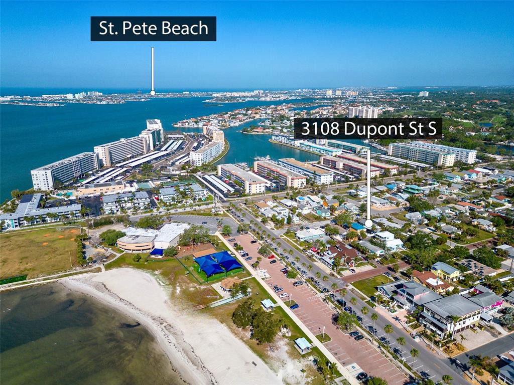 This aerial view shows a coastal neighborhood with a beach, residential buildings, and parking lots — 3108 DUPONT STREET S, GULFPORT, FL