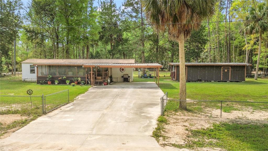 A single-story mobile home with a screened porch, carport, and a separate detached shed — 3650 SE 176TH PLACE, INGLIS, FL