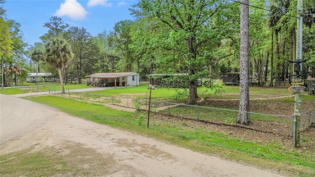 A single-story mobile home features a screened-in porch, a metal carport, and a concrete driveway — 3650 SE 176TH PLACE, INGLIS, FL