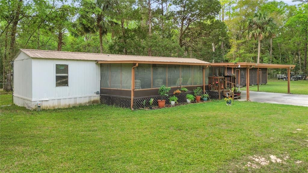 An aerial view shows a mobile home with a metal carport on a wooded lot — 3650 SE 176TH PLACE, INGLIS, FL