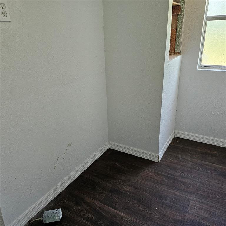 A corner of a room with dark wood-look flooring, white walls, and an unfinished wall opening — 2603 INCE DRIVE, RUSKIN, FL