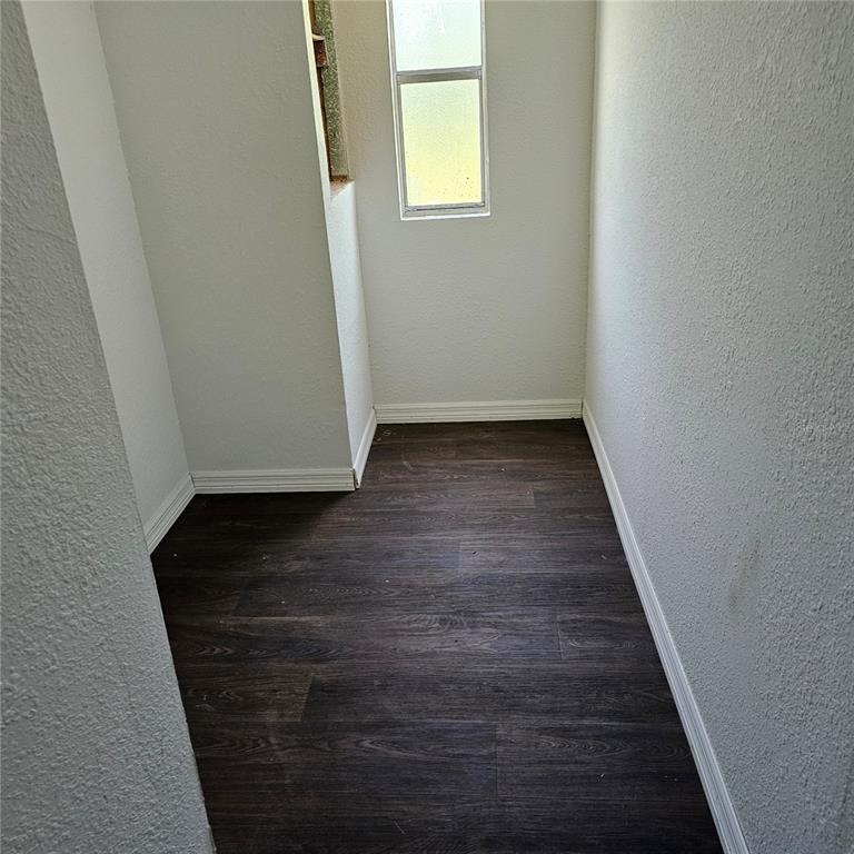 A small, empty room with dark wood-look flooring, white walls, and a single window — 2603 INCE DRIVE, RUSKIN, FL