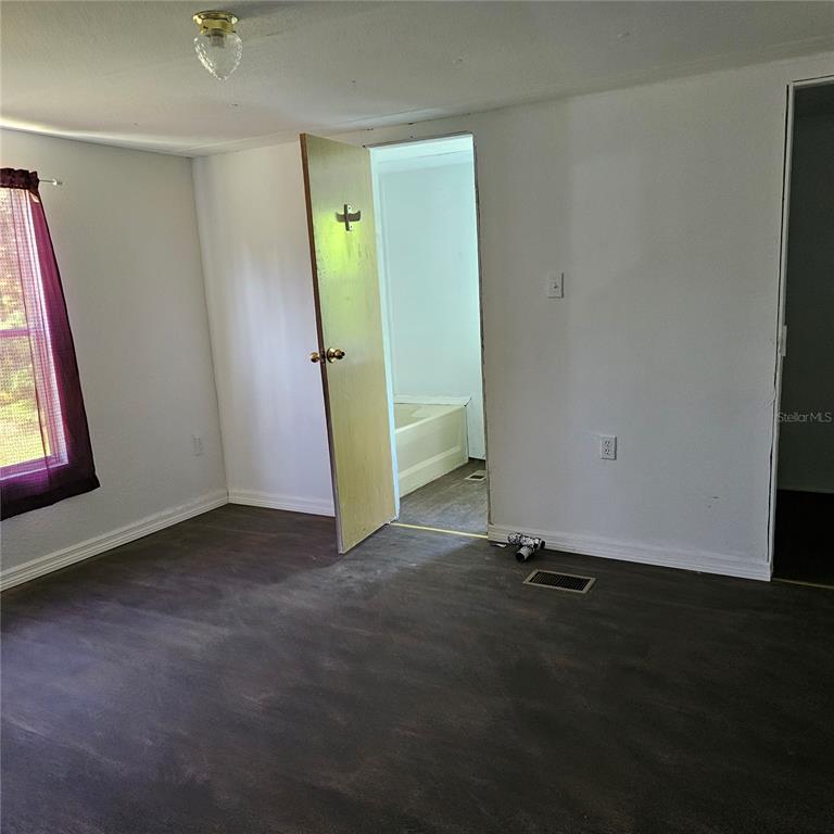 An interior room features dark flooring, white walls, a purple curtain, and an open doorway — 2603 INCE DRIVE, RUSKIN, FL