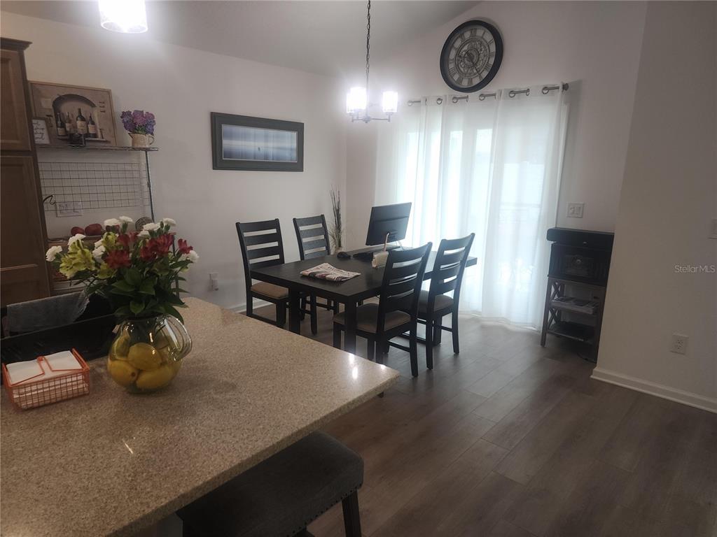 A dining area features a dark wood table, four chairs, and a granite-topped kitchen island — 7591 MERGAERT LANE, MIDDLETON, FL