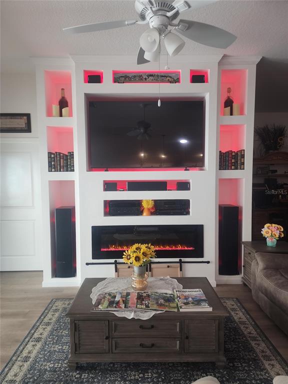 A living room features a built-in entertainment center with a television, fireplace, and red accent lighting — 7591 MERGAERT LANE, MIDDLETON, FL