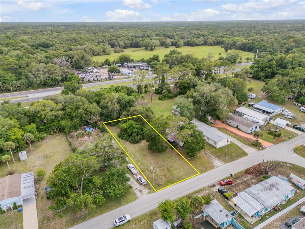 An aerial view shows a vacant, rectangular residential lot outlined in yellow near a road — NELLIE STREET, EDGEWATER, FL