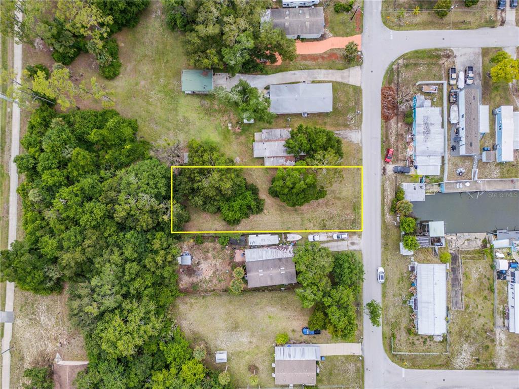 An aerial view shows a rectangular vacant lot outlined in yellow next to a road — NELLIE STREET, EDGEWATER, FL