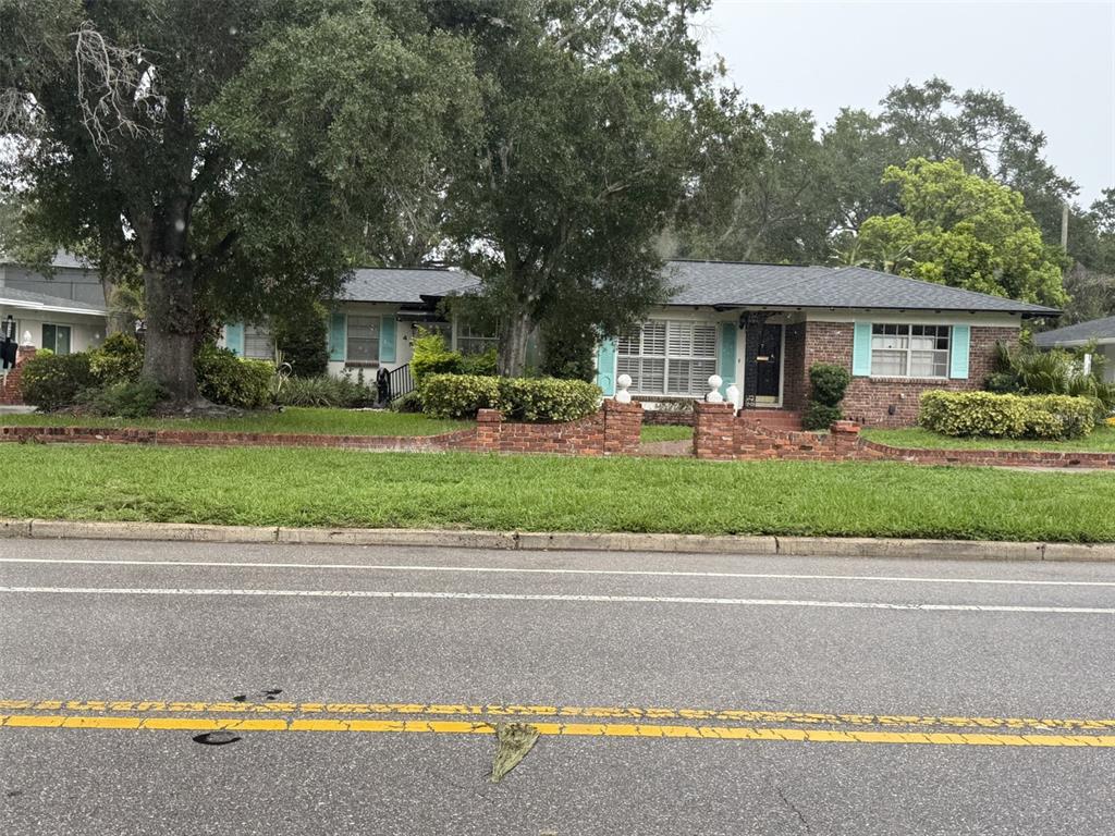 A single-story brick house with light blue shutters sits behind a low brick retaining wall — 451 W DAVIS BOULEVARD, TAMPA, FL