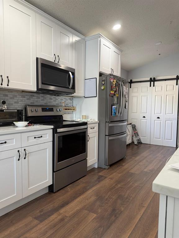 A kitchen features white cabinets, stainless steel appliances, a tiled backsplash, and wood-look flooring — 16425 GOLDEN EAGLE BOULEVARD, CLERMONT, FL