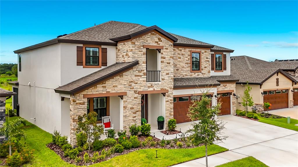 A front entryway features double doors with glass inserts, two potted topiaries, and stone siding — 13150 WELLSPRING DRIVE, LITHIA, FL
