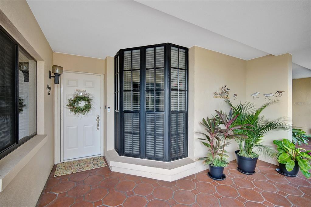A covered entryway features a white front door, a bay window, and potted plants — 7204 JESSIE HARBOR DRIVE UNIT 7204, OSPREY, FL