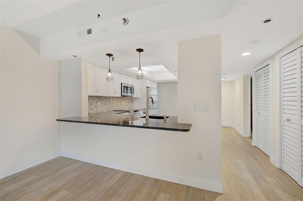 A kitchen with a granite breakfast bar, white cabinets, and light wood-look flooring — 7204 JESSIE HARBOR DRIVE UNIT 7204, OSPREY, FL