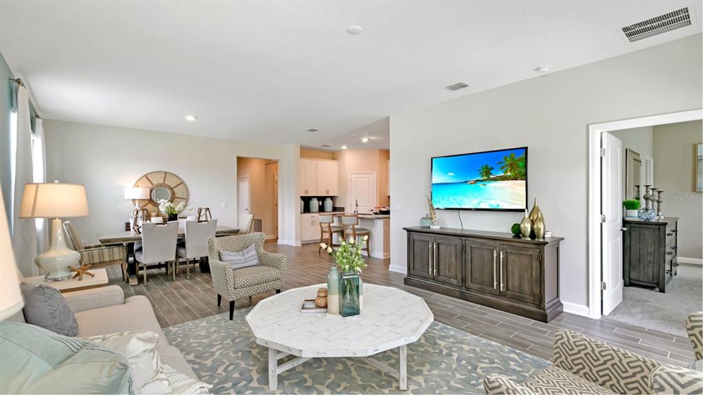 A living room with a television, a white coffee table, and an adjacent dining area — 3273 WHOLENESS WAY, CLERMONT, FL