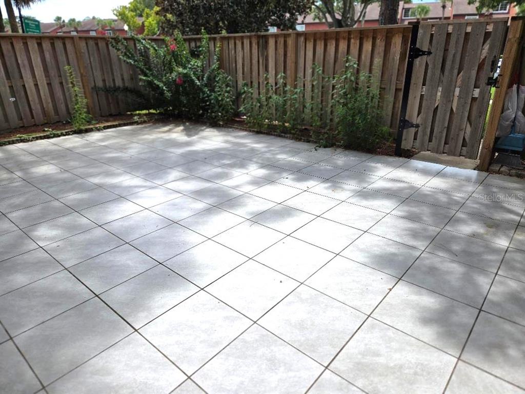 A paved patio area enclosed by a wooden fence with a gate — 5371 BAMBOO COURT UNIT 401, ORLANDO, FL