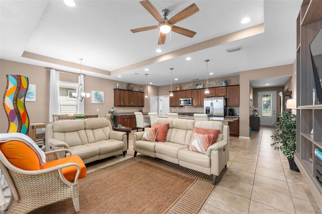 An open-concept living room and kitchen featuring tile floors, neutral walls, and wooden cabinetry — 5662 NW 40TH PL, OCALA, FL