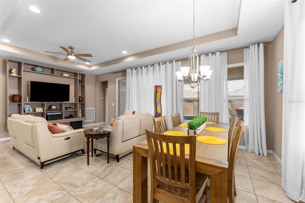 An open-concept living and dining area features tile flooring, a built-in entertainment center, and furniture — 5662 NW 40TH PL, OCALA, FL