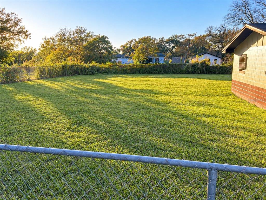 A single-story house with light siding and a dark roof sits behind a chain-link fence — 1112/1114 S BAY AVENUE, SANFORD, FL